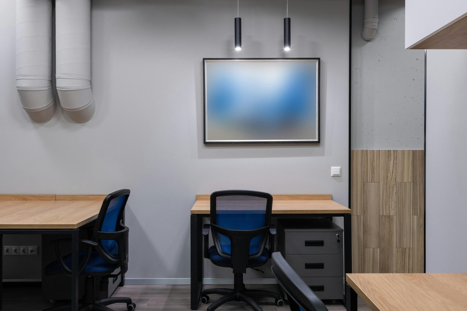 Interior of contemporary office space with blue chairs at wooden tables and gray walls